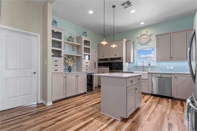 kitchen featuring pendant lighting, stainless steel appliances, light hardwood / wood-style floors, and a center island