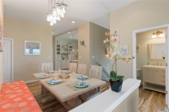 dining space featuring a chandelier, sink, and light hardwood / wood-style flooring