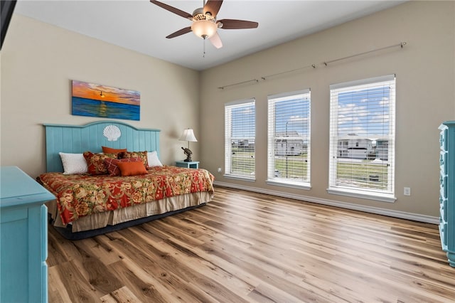 bedroom featuring multiple windows, ceiling fan, and light hardwood / wood-style flooring