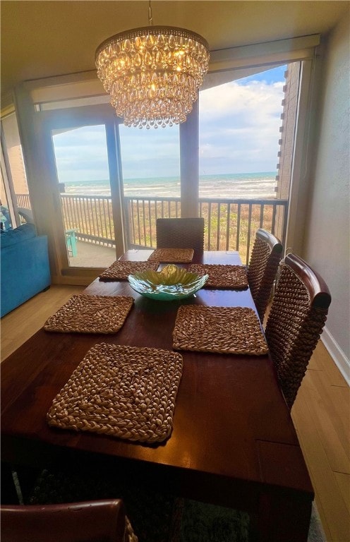 dining area featuring a water view, an inviting chandelier, and hardwood / wood-style flooring