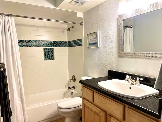 full bathroom featuring vanity, a textured ceiling, toilet, and shower / tub combo