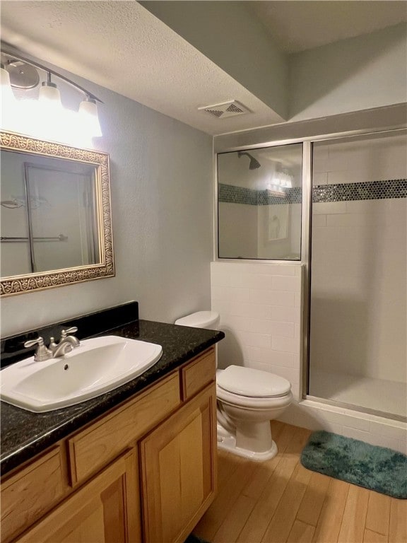 bathroom with walk in shower, wood-type flooring, vanity, and toilet