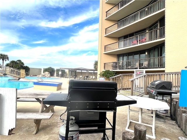 view of patio / terrace featuring a grill, a community pool, and a balcony