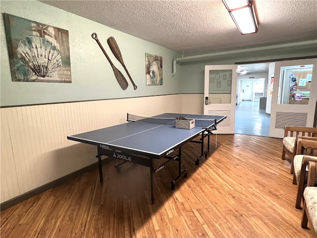 rec room featuring hardwood / wood-style flooring, ceiling fan, and a textured ceiling