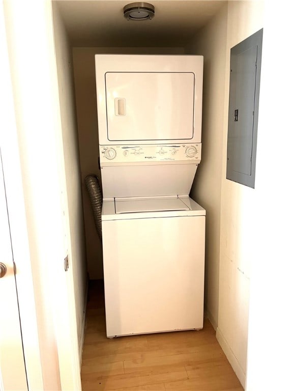 washroom featuring stacked washer / drying machine, electric panel, and light hardwood / wood-style floors