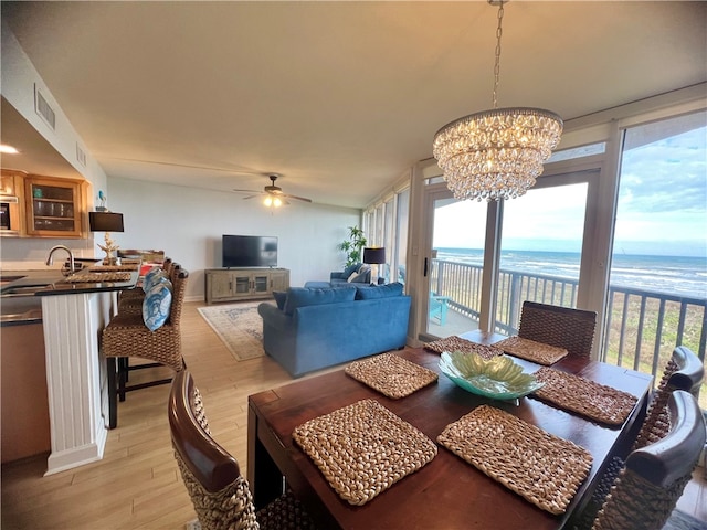 dining room with ceiling fan with notable chandelier, sink, and light hardwood / wood-style flooring