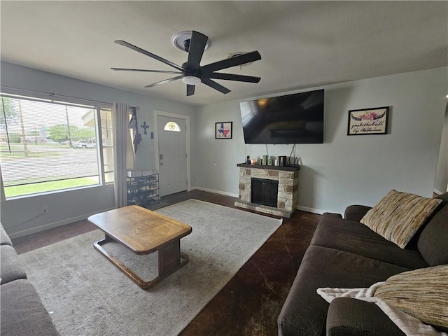 living area featuring baseboards, a ceiling fan, and a fireplace