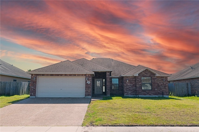 view of front of house featuring a garage, a shingled roof, concrete driveway, fence, and a front yard