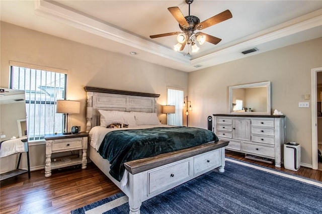 bedroom featuring dark hardwood / wood-style flooring, a tray ceiling, ceiling fan, and crown molding