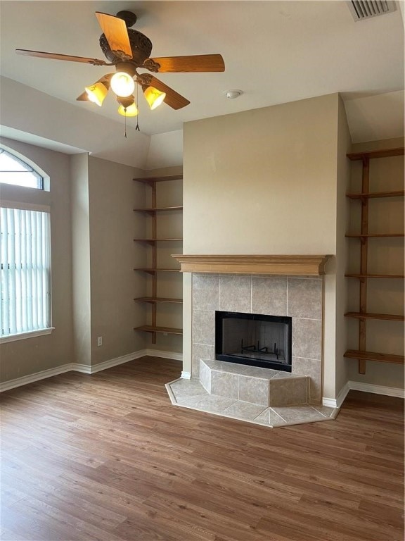 unfurnished living room featuring wood-type flooring, a tile fireplace, ceiling fan, and vaulted ceiling