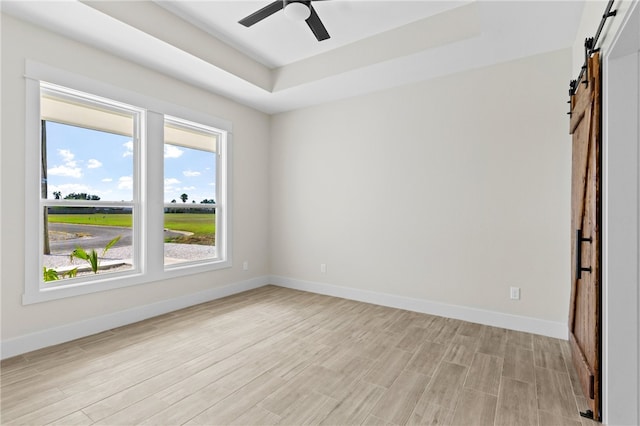 13942 Ketch St, Corpus Christi, TX 78418 - empty room featuring a barn door, a raised ceiling, light wood finished floors, and ceiling fan