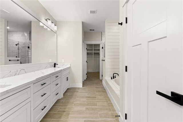 13942 Ketch St, Corpus Christi, TX 78418 - bathroom featuring double vanity, a shower stall, a bath, a spacious closet, and wood finished floors