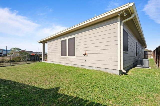 view of side of property with central air condition unit and a yard