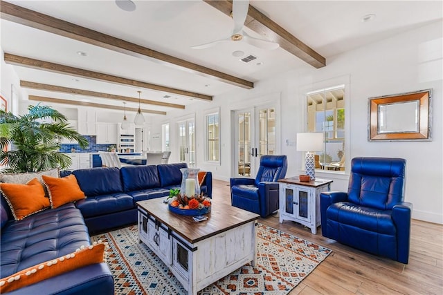 living room featuring baseboards, visible vents, beam ceiling, ceiling fan, and light wood-type flooring