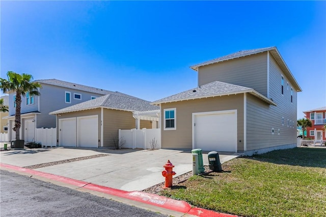 view of front of home with a garage, a front lawn, driveway, and fence