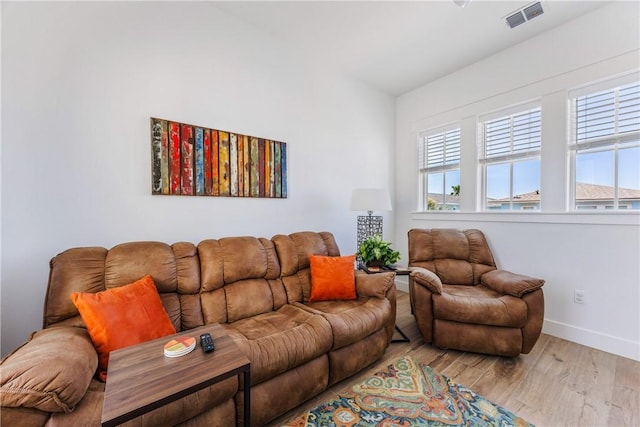 living area with plenty of natural light, light wood-style floors, visible vents, and baseboards