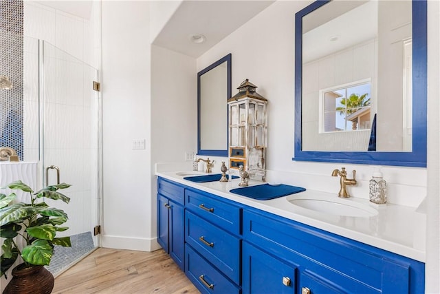 full bathroom with visible vents, a sink, wood finished floors, a shower stall, and double vanity