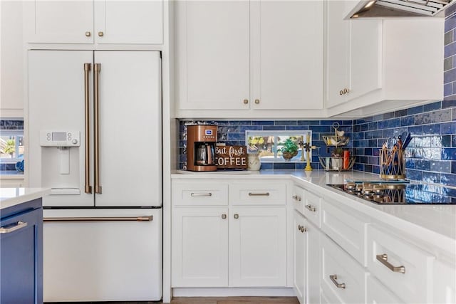 kitchen with tasteful backsplash, high end white fridge, under cabinet range hood, light countertops, and white cabinetry