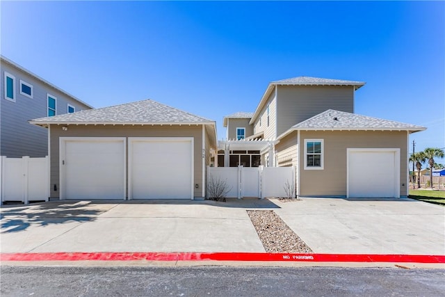 view of front facade featuring a shingled roof, concrete driveway, and fence