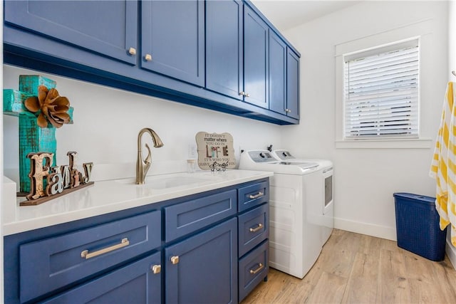 clothes washing area featuring baseboards, cabinet space, separate washer and dryer, a sink, and light wood-type flooring