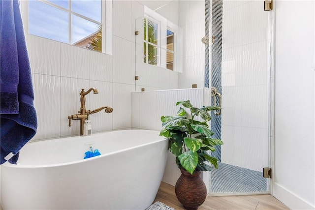 bathroom featuring a freestanding bath, tile walls, a stall shower, and wood finished floors