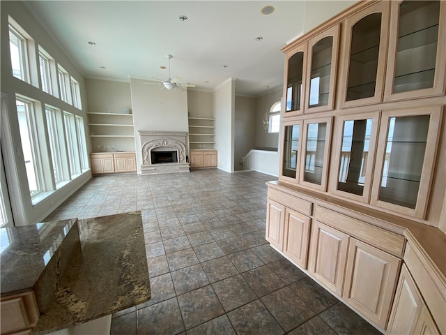 unfurnished living room featuring built in shelves, ornamental molding, and ceiling fan