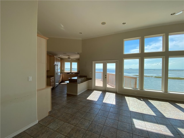 empty room featuring dark tile patterned floors, ceiling fan, a water view, and ornamental molding