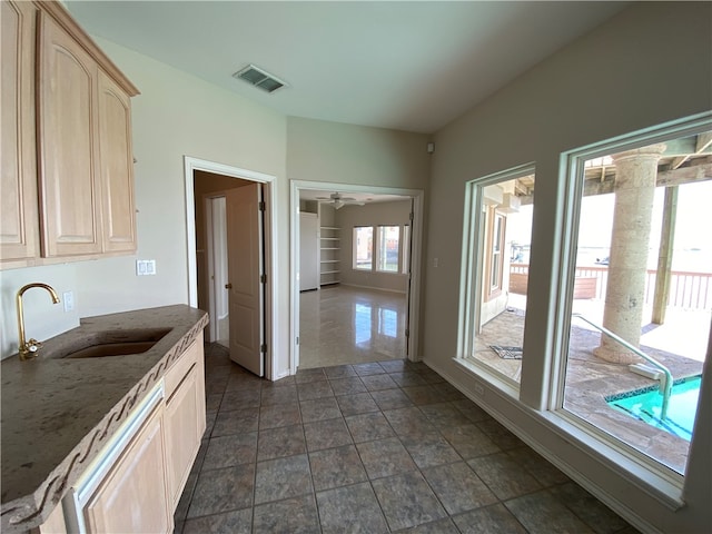 kitchen featuring sink, stone counters, ceiling fan, dark tile patterned floors, and light brown cabinetry