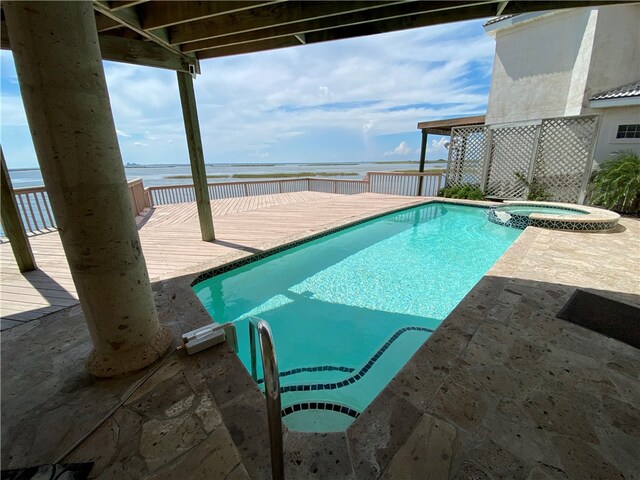 view of swimming pool with a water view and an in ground hot tub