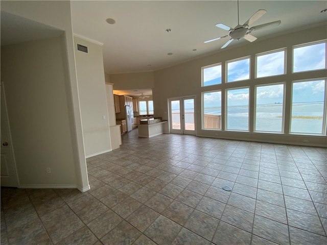 tiled empty room with ornamental molding, a water view, and ceiling fan