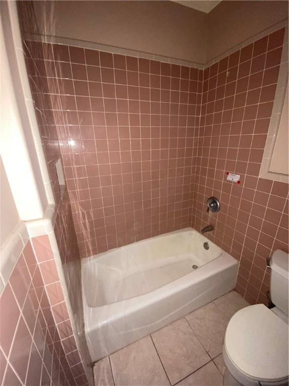 bathroom with tub / shower combination, tile walls, tile patterned floors, and toilet