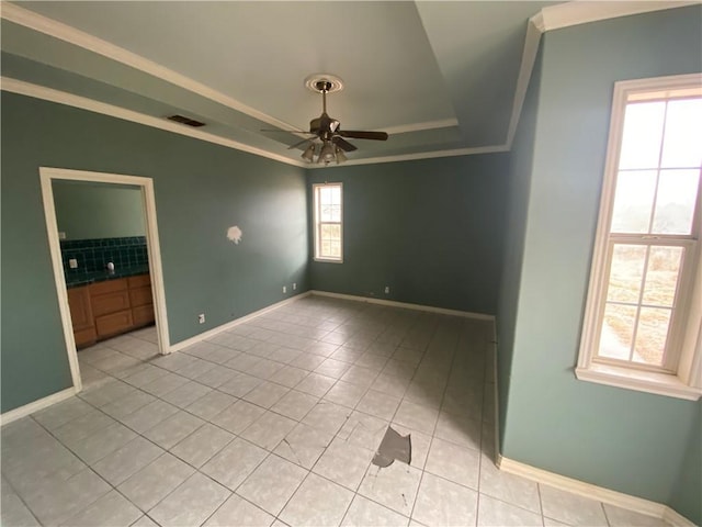 tiled empty room featuring crown molding, ceiling fan, and a tray ceiling