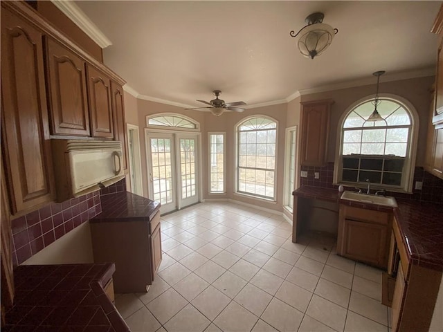 kitchen with light tile patterned flooring, pendant lighting, tasteful backsplash, sink, and ornamental molding