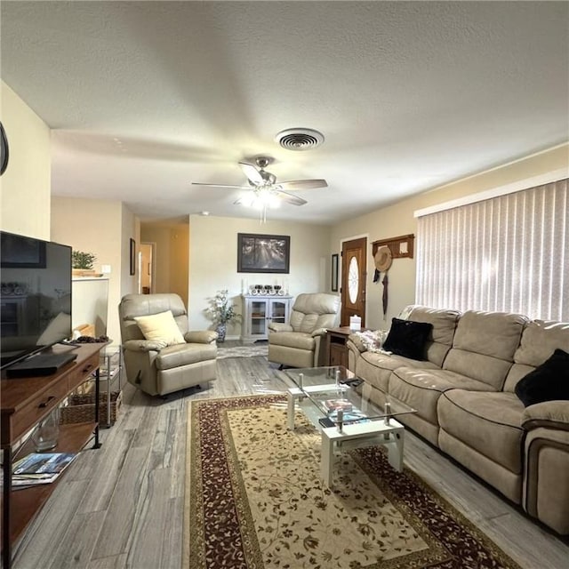 living room with hardwood / wood-style flooring, ceiling fan, and a textured ceiling