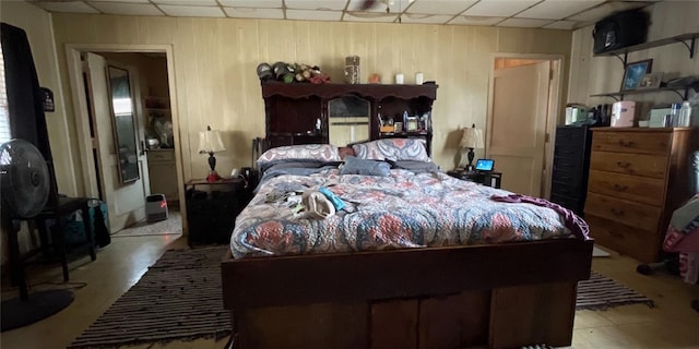 bedroom with a paneled ceiling and wooden walls