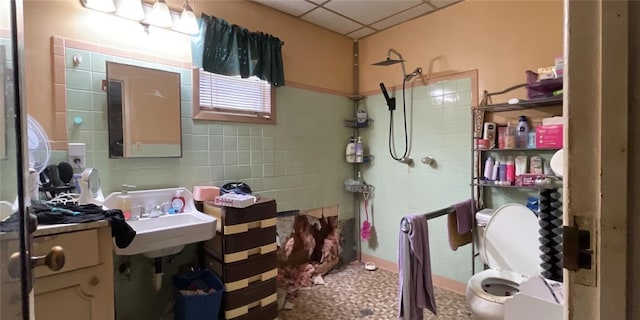 bathroom featuring tile walls, sink, a shower, and a drop ceiling