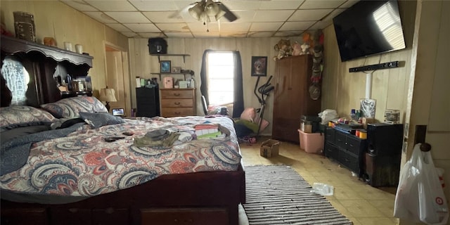 bedroom featuring a drop ceiling and wood walls