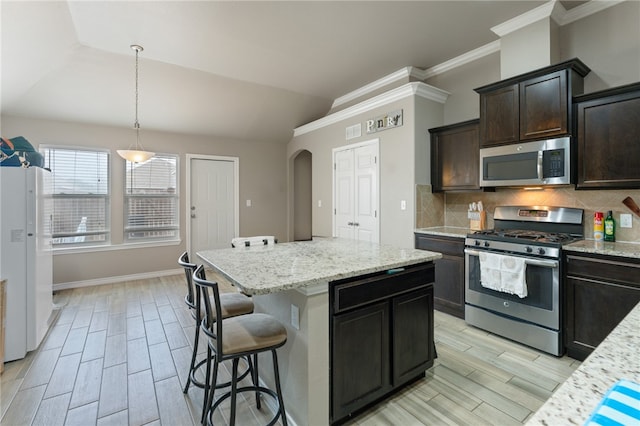 kitchen featuring tasteful backsplash, appliances with stainless steel finishes, hanging light fixtures, vaulted ceiling, and a center island