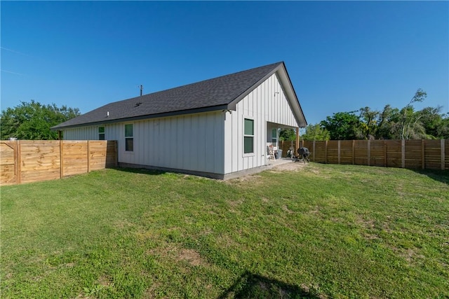 rear view of house featuring board and batten siding, a yard, and a fenced backyard