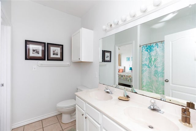 bathroom with toilet, double vanity, a sink, and tile patterned floors