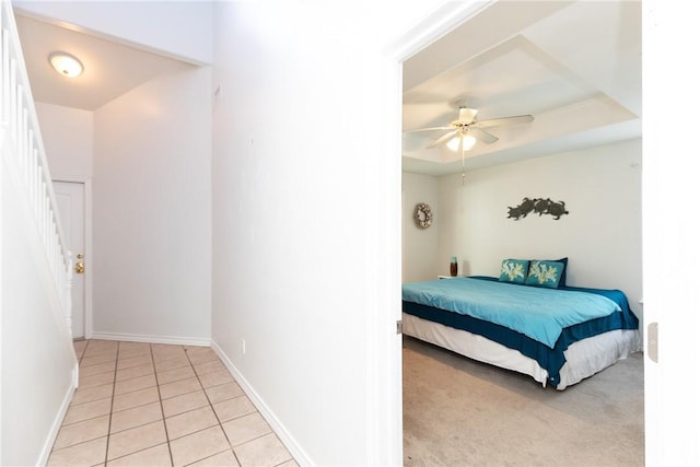 bedroom with baseboards, a tray ceiling, a ceiling fan, and light tile patterned flooring