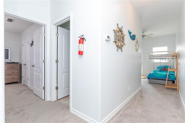 hall with carpet floors, baseboards, and visible vents