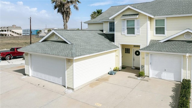 view of front of property featuring a garage, concrete driveway, and roof with shingles