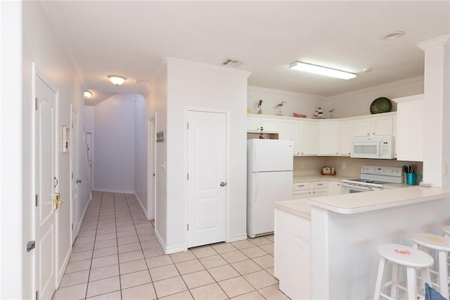 kitchen with light tile patterned floors, a peninsula, white appliances, visible vents, and ornamental molding