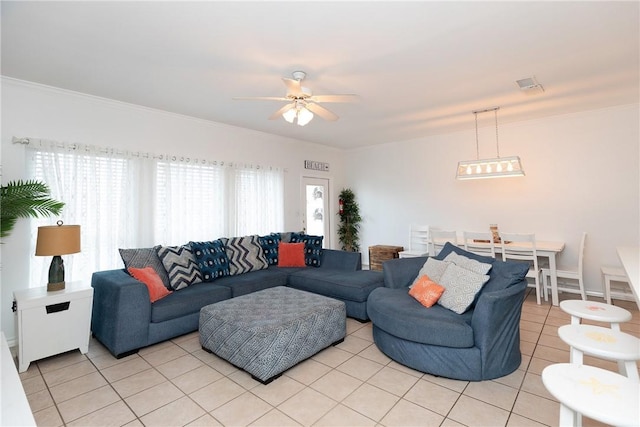 living area with light tile patterned floors, ceiling fan, ornamental molding, and visible vents