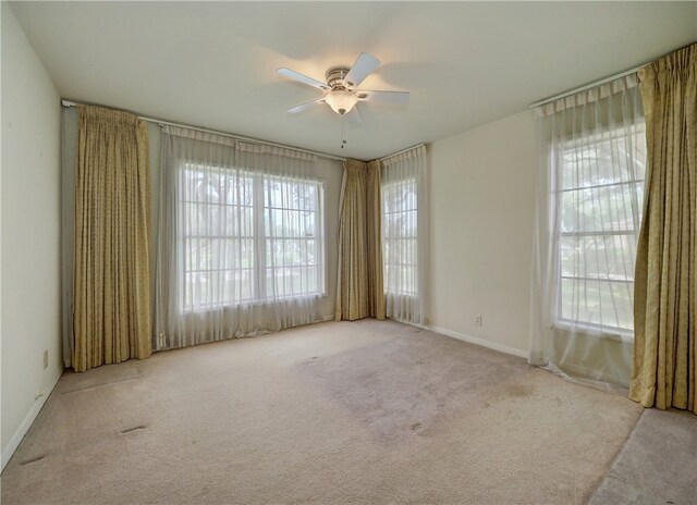 unfurnished room featuring ceiling fan, plenty of natural light, and light carpet