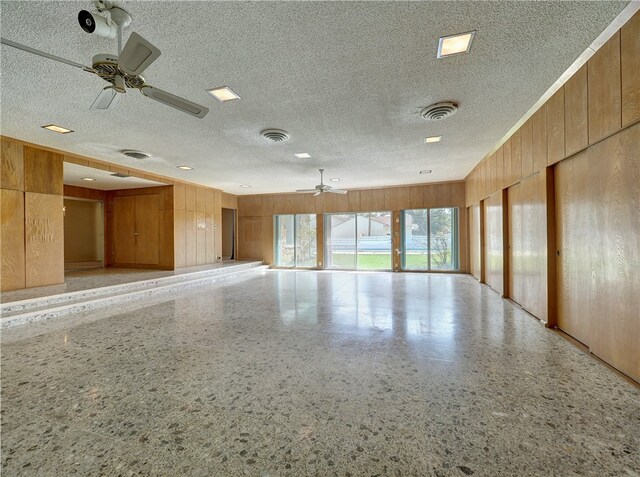 spare room featuring wood walls, ceiling fan, and a textured ceiling