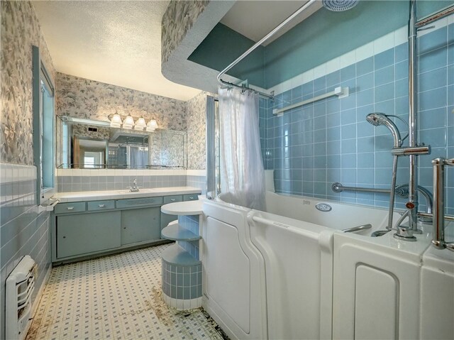 full bathroom featuring vanity, tiled shower / bath, toilet, and tile walls