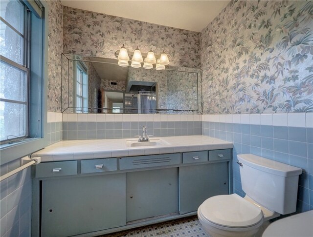 bathroom with toilet, vanity, and tile walls