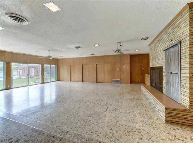 unfurnished room featuring wooden walls, a textured ceiling, and ceiling fan